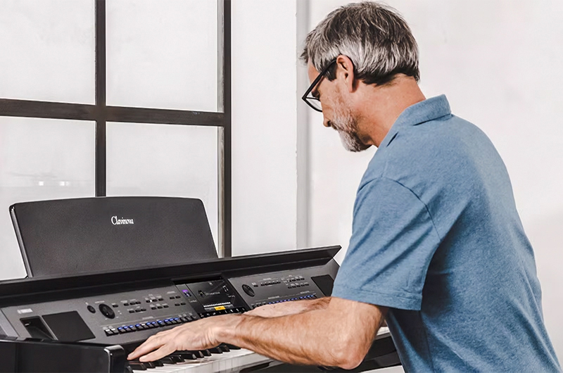 Man playing a Yamaha Clavinova digital piano, showcasing advanced features and high-quality sound at Classic Pianos Denver.