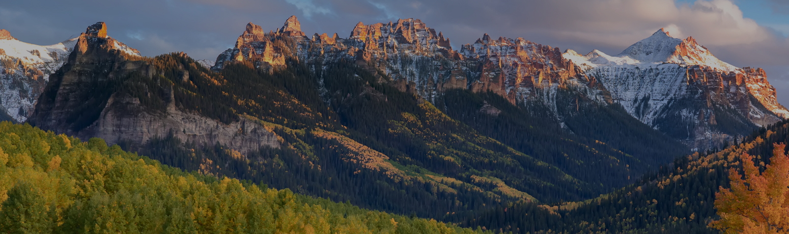 Mountainous landscape with lush green forests at sunset, capturing Colorado's natural beauty near Classic Pianos Denver.