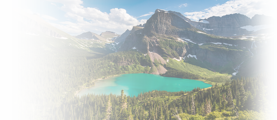 Mountain lake surrounded by lush forest and mountains under a blue sky. Ideal retreat for inspiration and creativity.