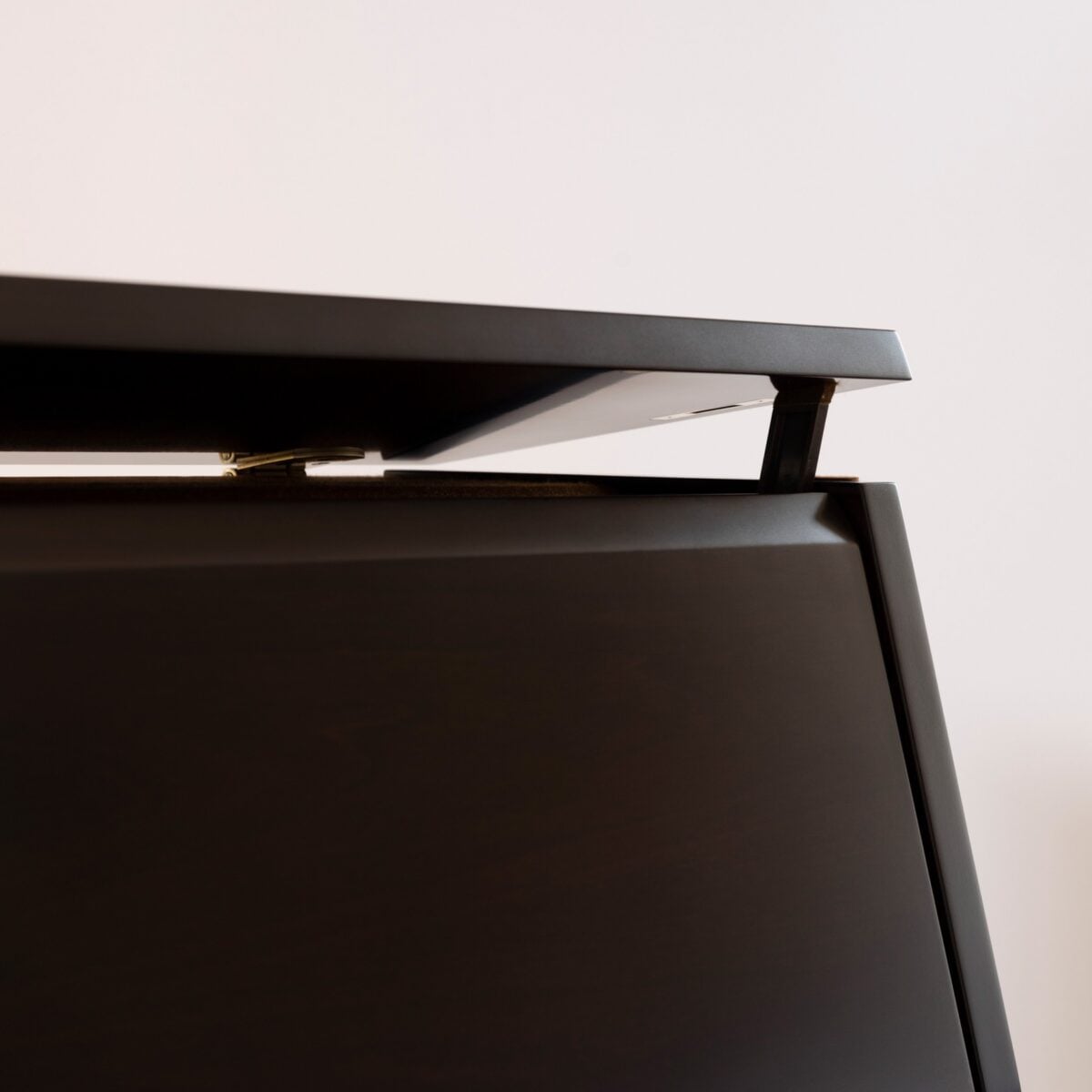 Close-up of a polished ebony piano lid hinge showcasing sleek design at Classic Pianos Denver.