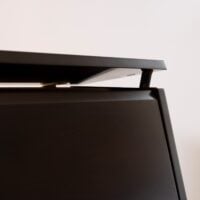 Close-up of a polished ebony piano lid hinge showcasing sleek design at Classic Pianos Denver.