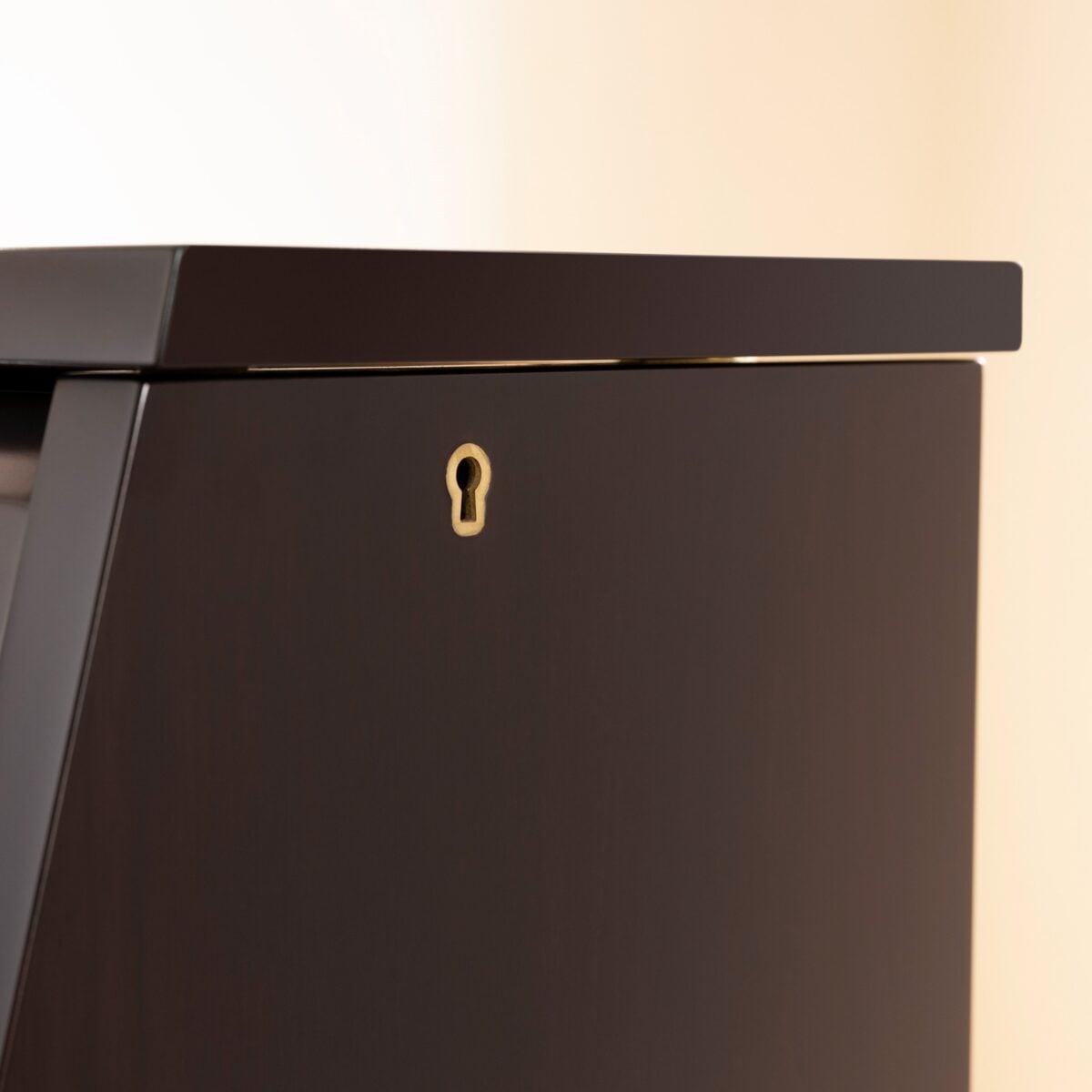Glossy ebony upright piano cabinet corner detail with keyhole lock, showcasing premium craftsmanship and elegant design.