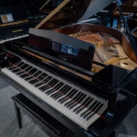 Close-up of a glossy grand piano featuring premium ebony finish, intricate action design, and polished keys for superior sound.