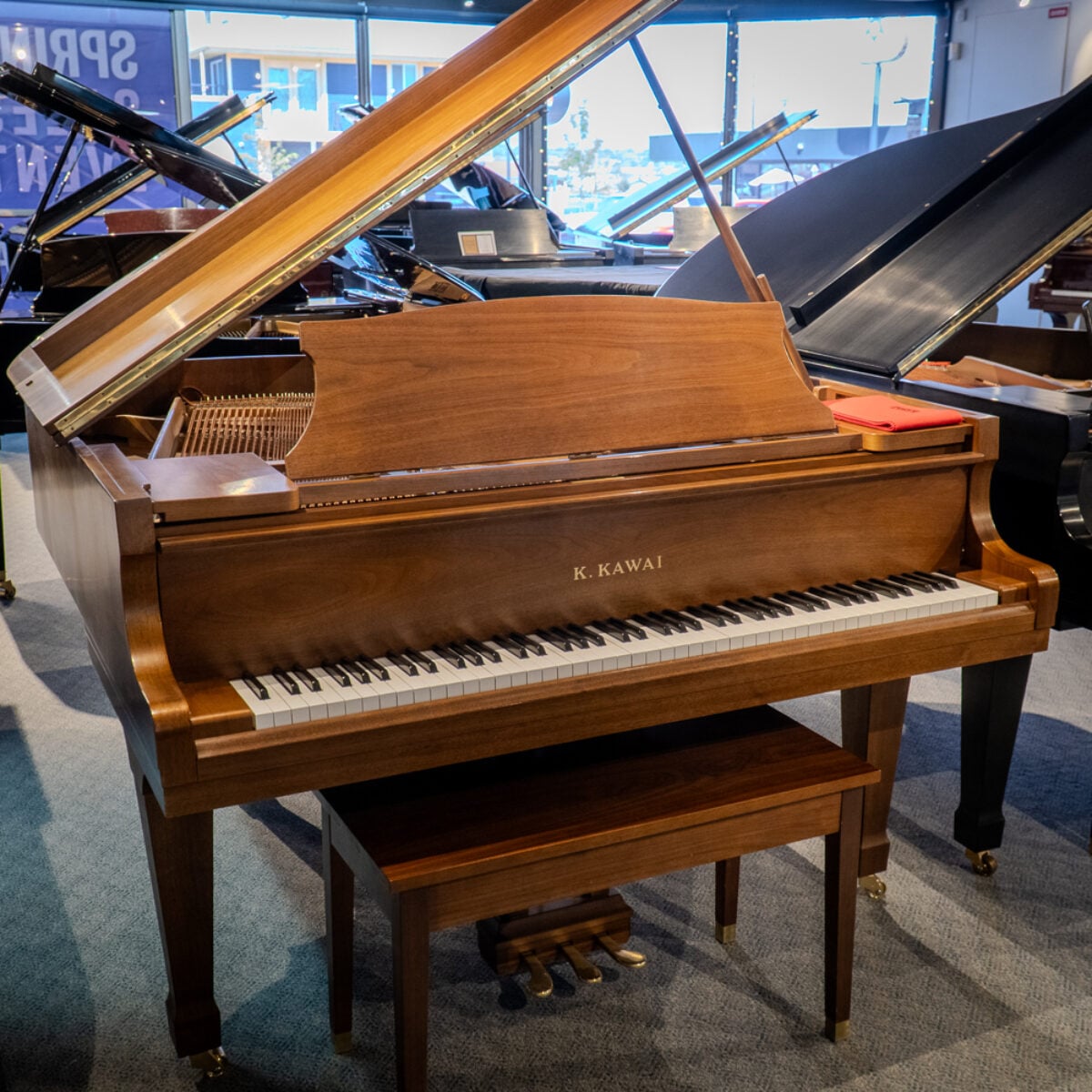 **Alt Text:** Kawai grand piano in mahogany finish featuring a polished lid, premium keys, and elegant design at Classic Pianos Denver.