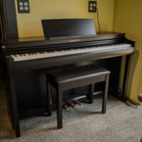 Yamaha digital piano with polished ebony finish, featuring 88 weighted keys and matching bench, perfect for any musician.