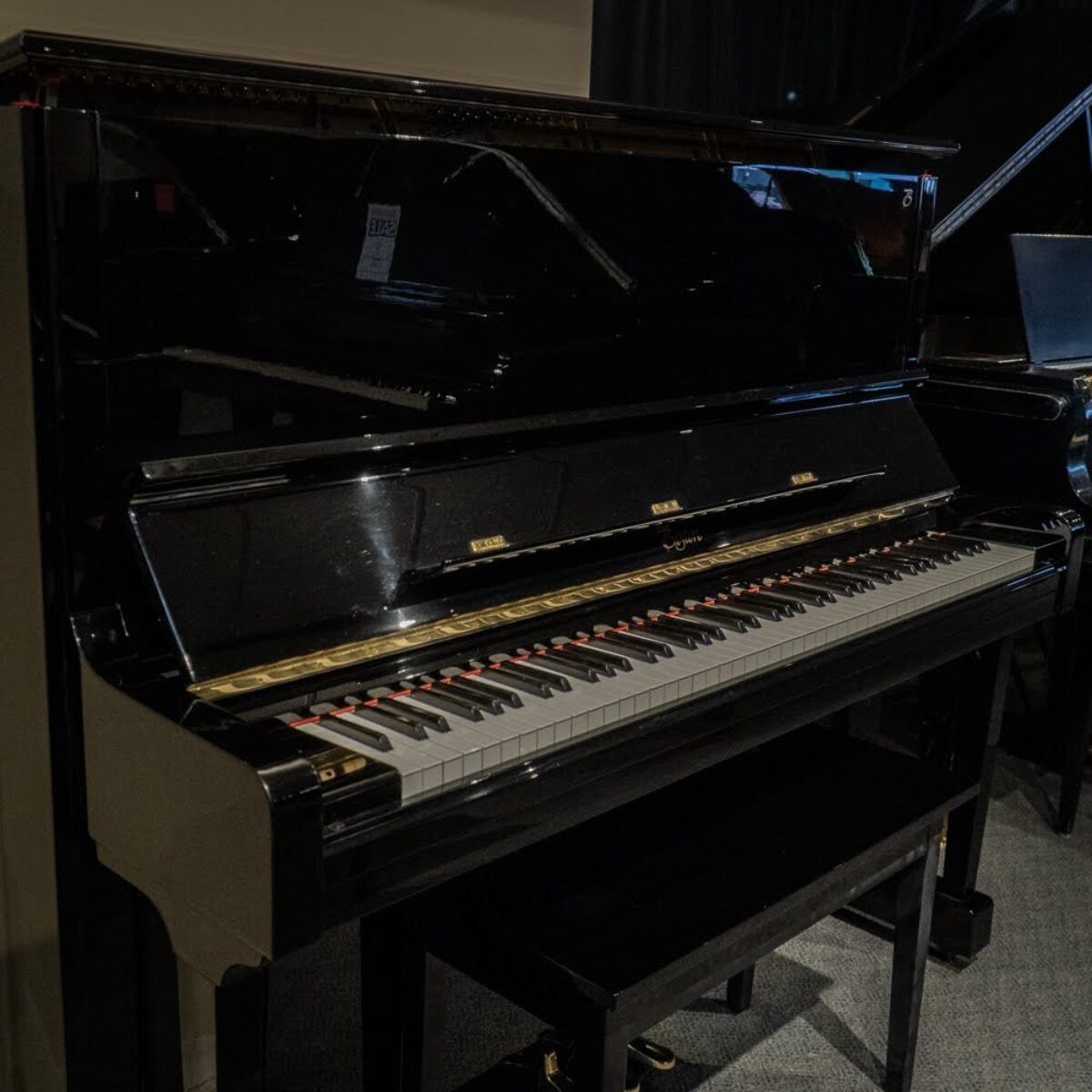 High-gloss black upright piano showcasing polished keys and premium craftsmanship, ideal for both beginners and professionals.