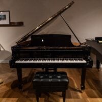 Alt text: Steinway grand piano with polished ebony finish, featuring a matching bench, at Classic Pianos Denver showroom.