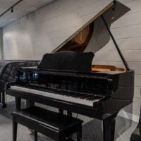 Alt text: Yamaha baby grand piano with polished ebony finish, showcasing white keys and elegant design, ideal for any space.