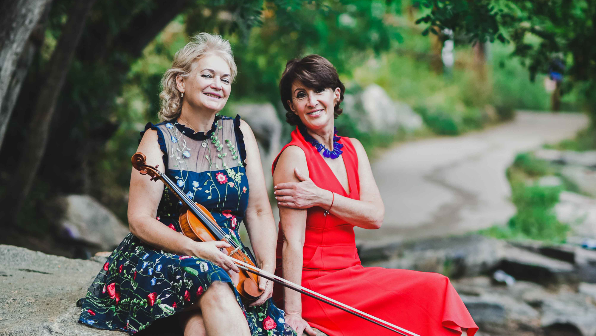Two musicians outdoors, one holds a violin, showcasing the artistry behind piano performance at Classic Pianos.