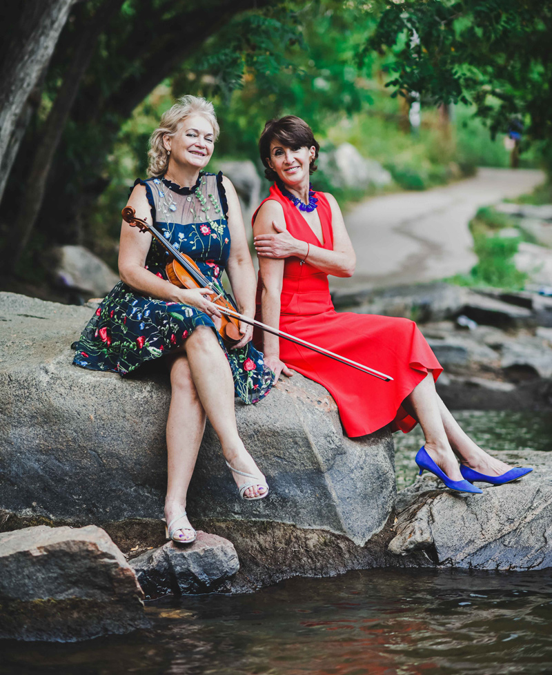 Two musicians sharing a moment, one holding a violin, celebrating the joy of music and performance artistry.
