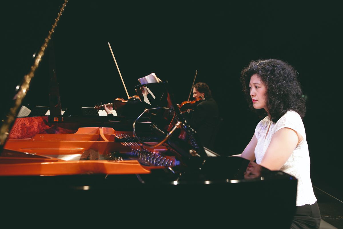 Smiling girl playing on a grand piano Piano being played with violin and other accompaniment