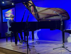A pianist performs on a Yamaha CFX grand piano, showcasing its rich sound and craftsmanship in a vibrant setting.